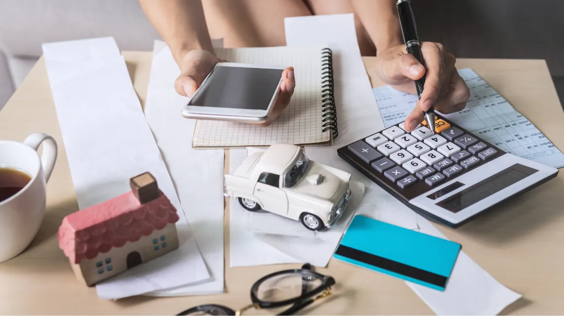 Osoba licząca koszty za pomocą kalkulatora i smartfona